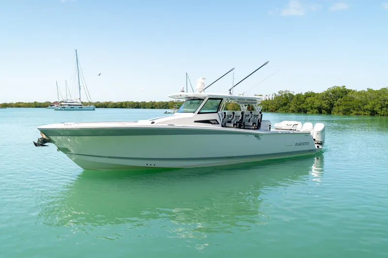 Slide: The Image of 2024 Blackfin 400 CC boat on calm water, clear sky, and lush background. - 3