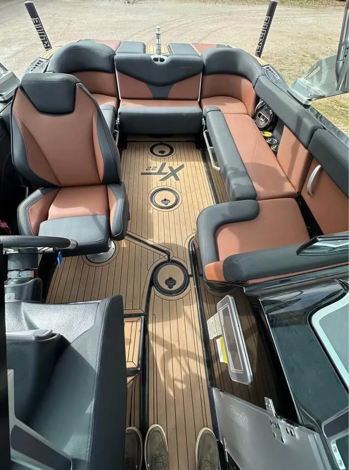 Slide: The Image of 2021 MasterCraft XT22 boat interior with brown and black seating, teak flooring. - 5
