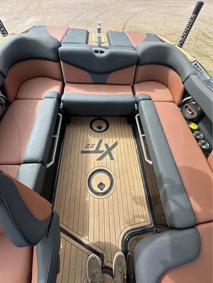 Slide: The Image of 2021 MasterCraft XT22 boat interior with brown and gray seating, teak flooring. - 6