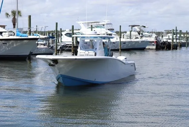 Slide: The Image of 2019 Tidewater 320 CC Adventure boat docked in a marina with other vessels. - 1