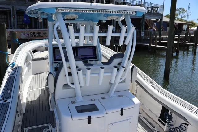 Slide: The Image of 2019 Tidewater 320 CC Adventure boat with rod holders and navigation screens at a dock. - 14