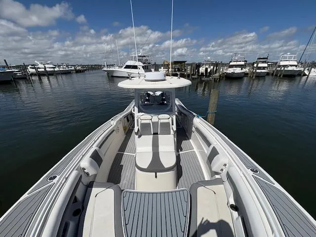 Slide: The Image of 2019 Tidewater 320 CC Adventure boat docked in a marina under a clear blue sky. - 7
