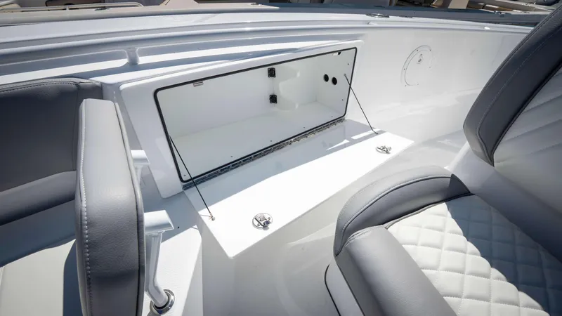 Slide: The Image of 2025 Everglades 335 CC boat interior with open storage compartment and cushioned seating. - 10