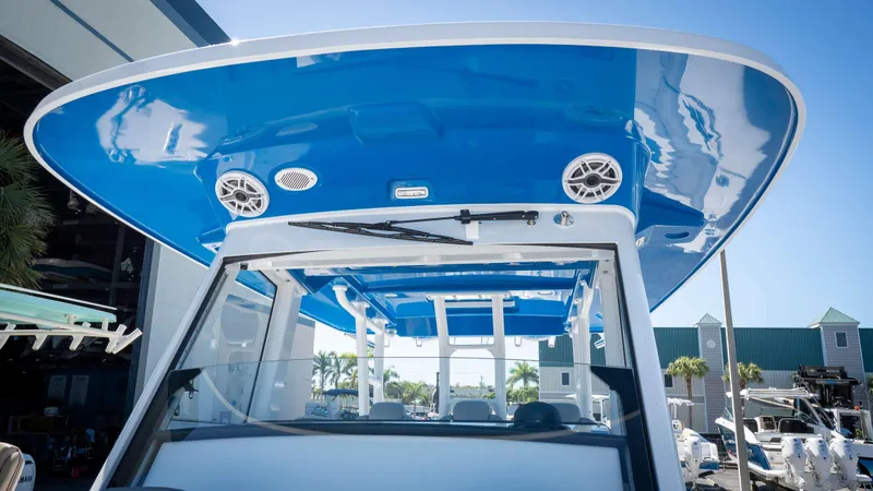Slide: The Image of 2025 Everglades 335 CC boat with blue canopy and speakers, docked under clear sky. - 14