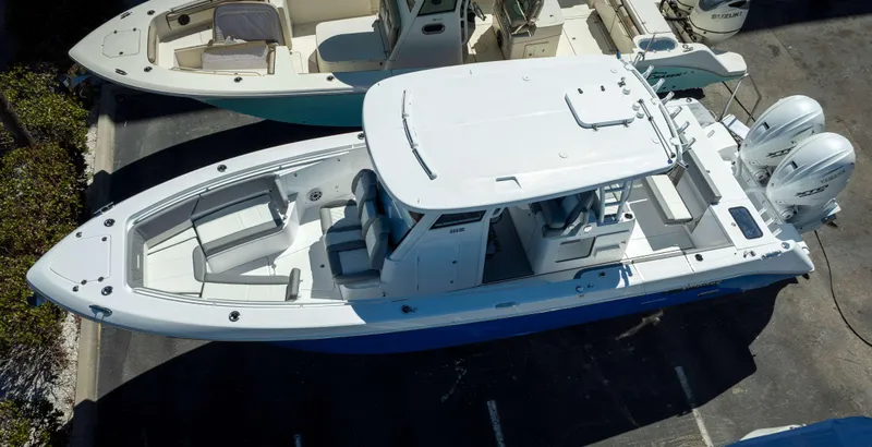Slide: The Image of 2025 Everglades 335 CC boat with dual engines, aerial view in a parking area. - 2
