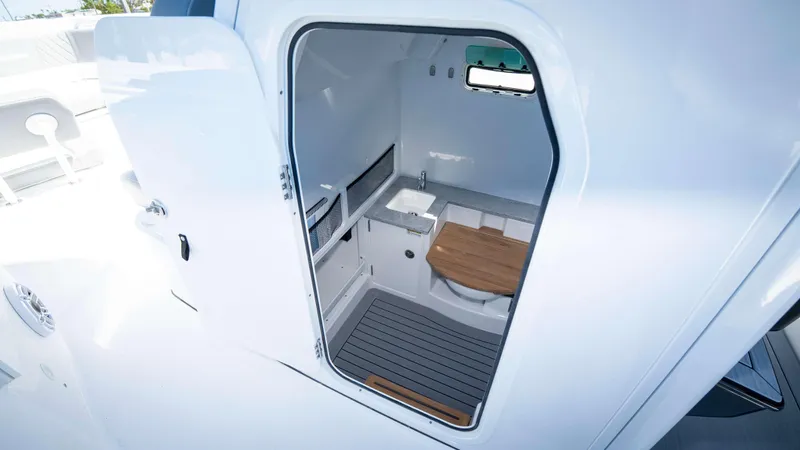 Slide: The Image of Interior of 2025 Everglades 335 CC boat, featuring a compact cabin with sink and seating. - 23