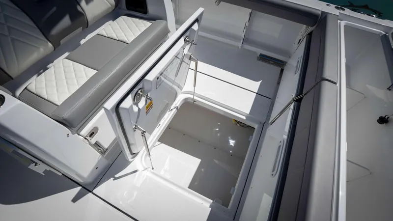 Slide: The Image of 2025 Everglades 335 CC boat interior with open storage compartments and cushioned seating. - 47