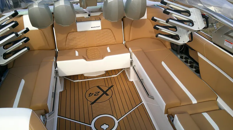 Slide: The Image of 2025 MasterCraft X24 boat interior with tan seating and wood-style flooring. - 4
