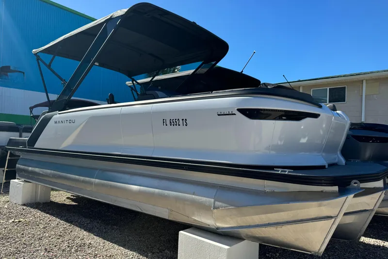 The Image of 2024 Manitou 22' Cruise Max Switchback pontoon boat with canopy, displayed outdoors. - 0