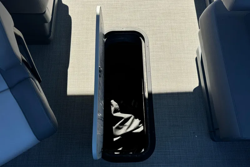 Slide: The Image of 2024 Manitou 22' Cruise Max Switchback storage compartment open on boat floor. - 16