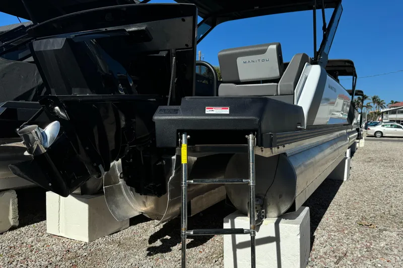 Slide: The Image of 2024 Manitou 22' Cruise Max Switchback boat on display, rear view with ladder. - 17