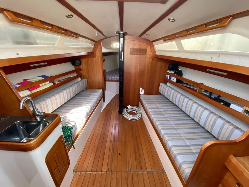 Slide: The Image of Interior of a 2013 Tartan 101 sailboat with wooden flooring and striped seating. - 12