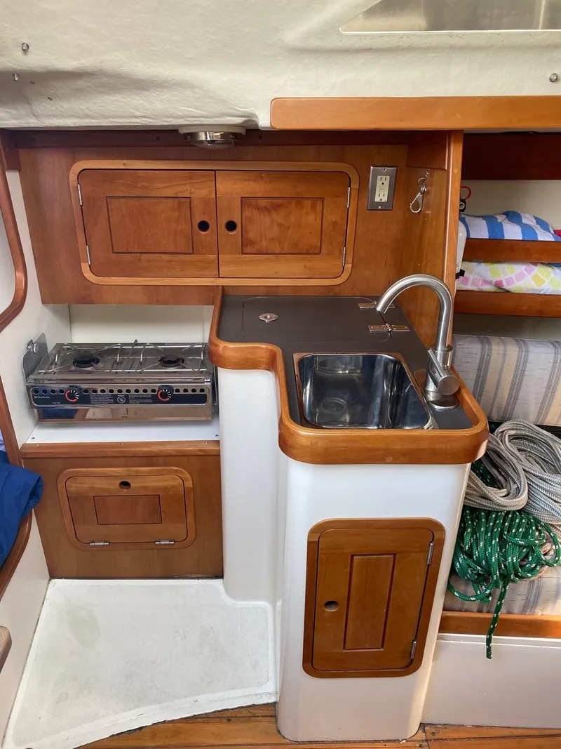 Slide: The Image of Compact kitchen area in a 2013 Tartan 101 sailboat with stove, sink, and storage. - 13
