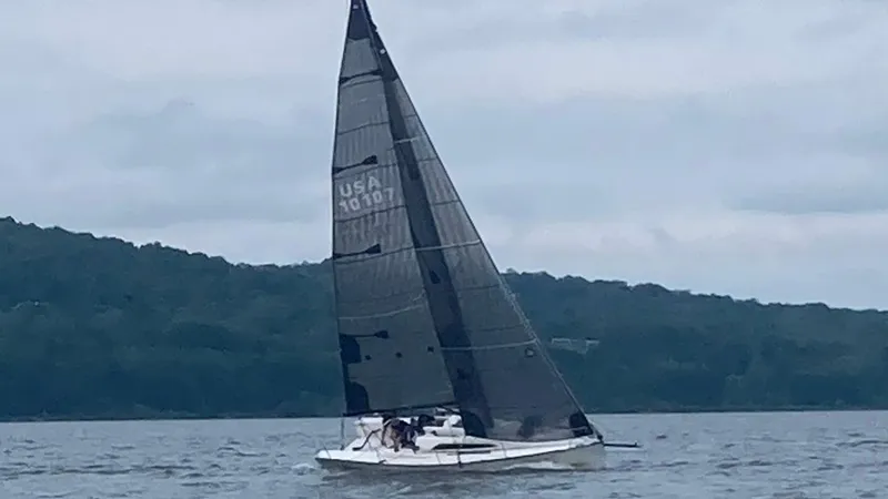 Slide: The Image of Sailboat Tartan 101 from 2013 on a calm lake with forested shoreline. - 2