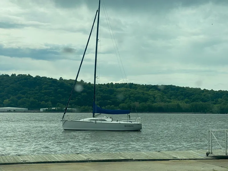 Slide: The Image of Sailboat Tartan 101 (2013) on calm water near a wooded shoreline. - 6