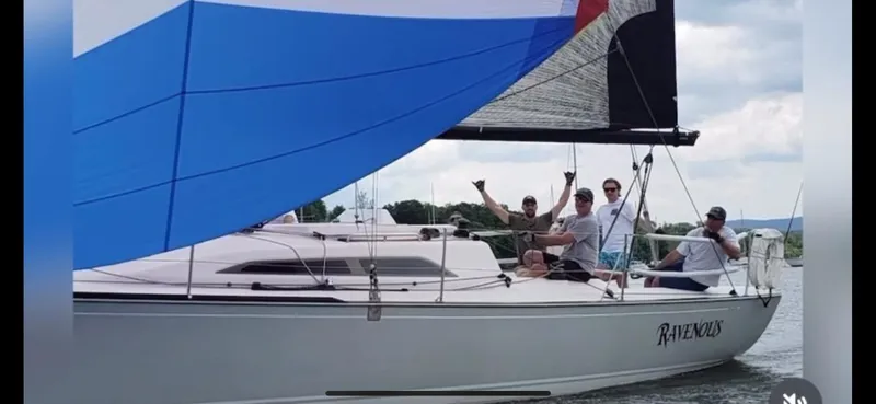 Slide: The Image of Sailboat Tartan 101, 2013 model, with crew sailing on a lake under a blue spinnaker. - 7