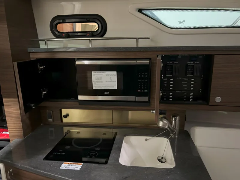 Slide: The Image of 2025 Boston Whaler 325 Conquest galley with microwave, stove, and sink. - 15