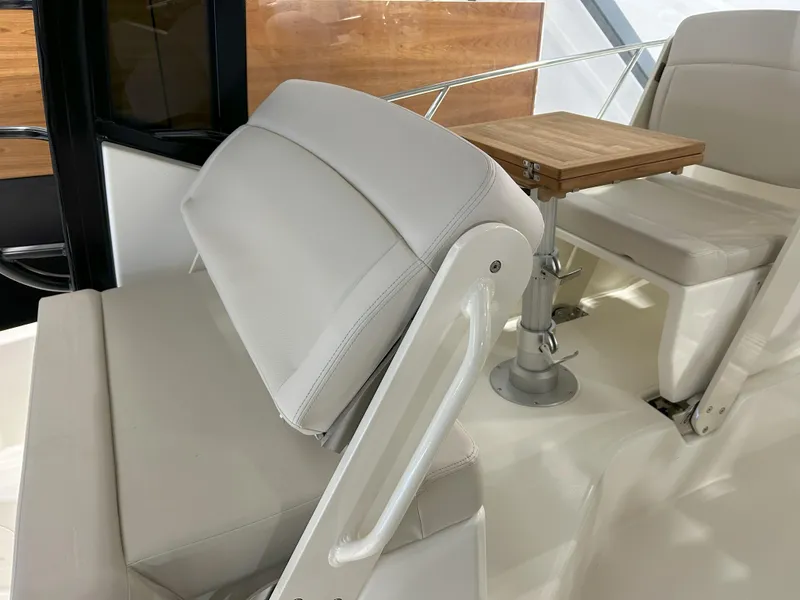 Slide: The Image of 2025 Boston Whaler 325 Conquest interior seating with adjustable backrest and wooden table. - 35