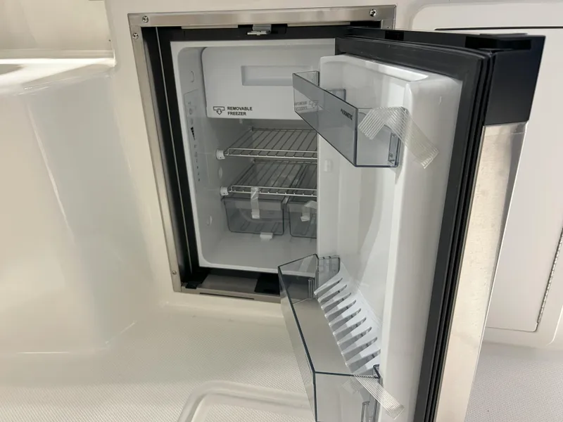 Slide: The Image of Open refrigerator on 2025 Boston Whaler 325 Conquest boat, showcasing interior shelves and storage. - 38