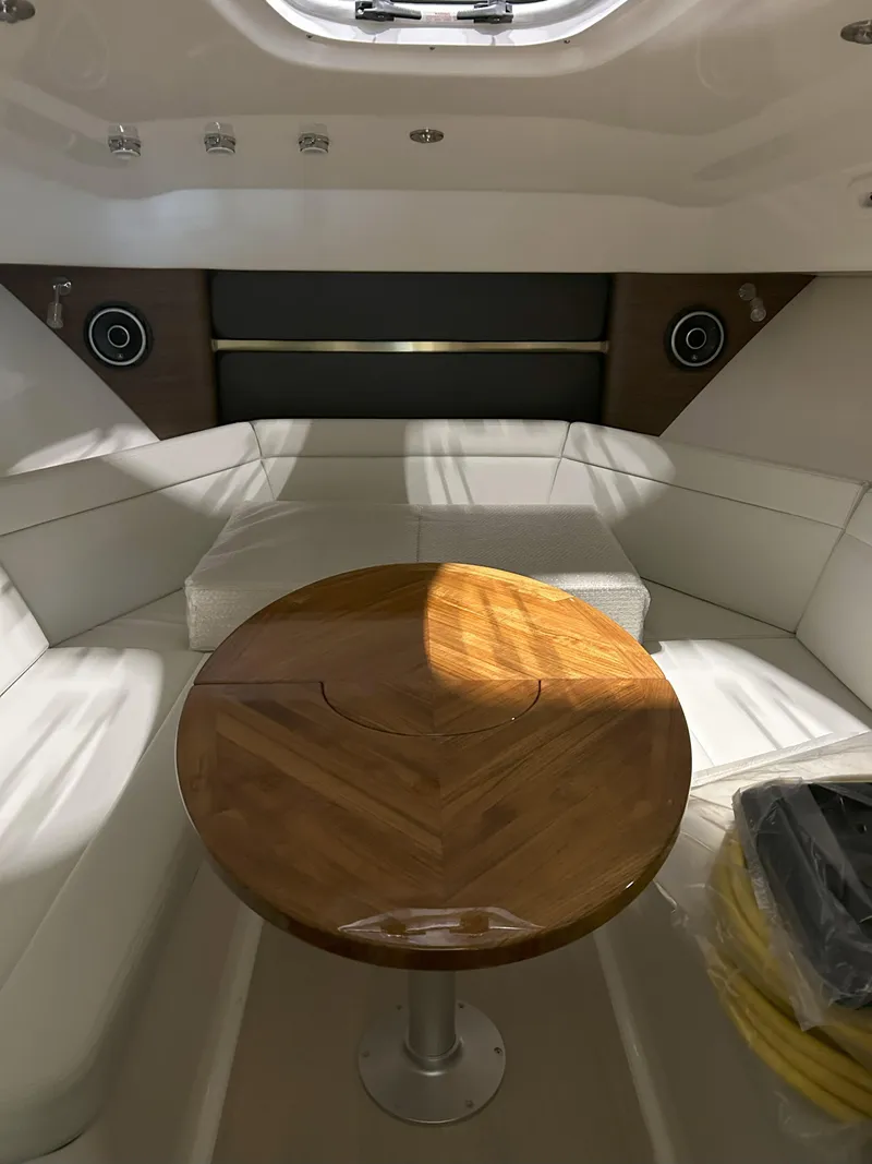 Slide: The Image of 2025 Boston Whaler 325 Conquest cabin interior with wooden table and white seating. - 7