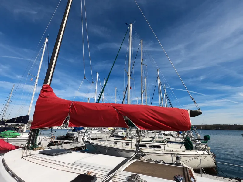Slide: The Image of Sailboats docked at marina under blue sky, featuring a 1984 Freedom 32 with red sail cover. - 27