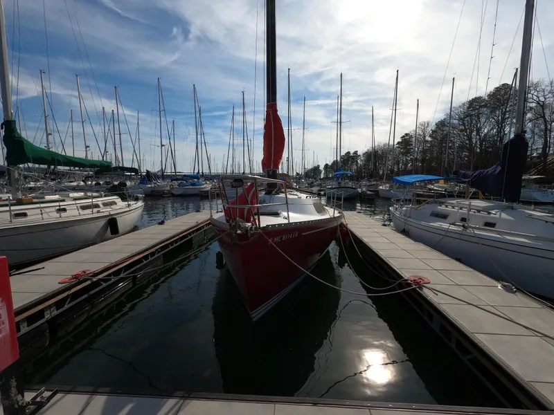 Slide: The Image of Red Freedom 32 sailboat docked at marina, surrounded by other boats, under a partly cloudy sky. - 29