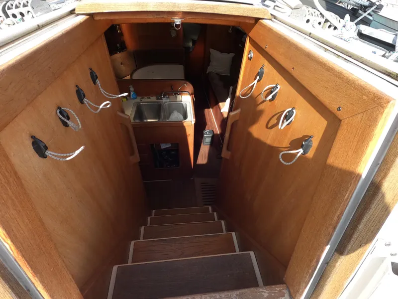 Slide: The Image of Interior view of 1984 Freedom 32 sailboat, featuring wooden stairs and compact kitchen area. - 6