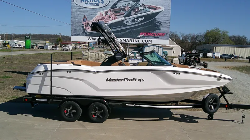 Slide: The Image of 2025 MasterCraft NXT22 boat on trailer, displayed outdoors with promotional billboard. - 1
