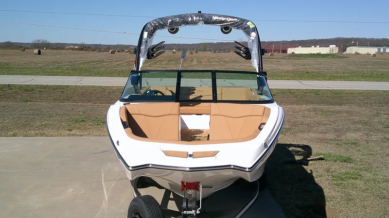 Slide: The Image of 2025 MasterCraft NXT22 boat with tan interior, parked on a concrete surface. - 3