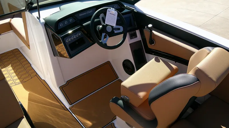 Slide: The Image of 2025 MasterCraft NXT22 boat interior with tan and black seating, modern dashboard, and steering wheel. - 7