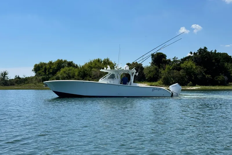 Slide: The Image of 2014 Yellowfin 42 Offshore boat cruising on a sunny day near lush shoreline. - 2