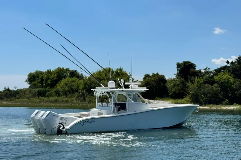 Slide: The Image of 2014 Yellowfin 42 Offshore boat cruising on a sunny day near a lush shoreline. - 3