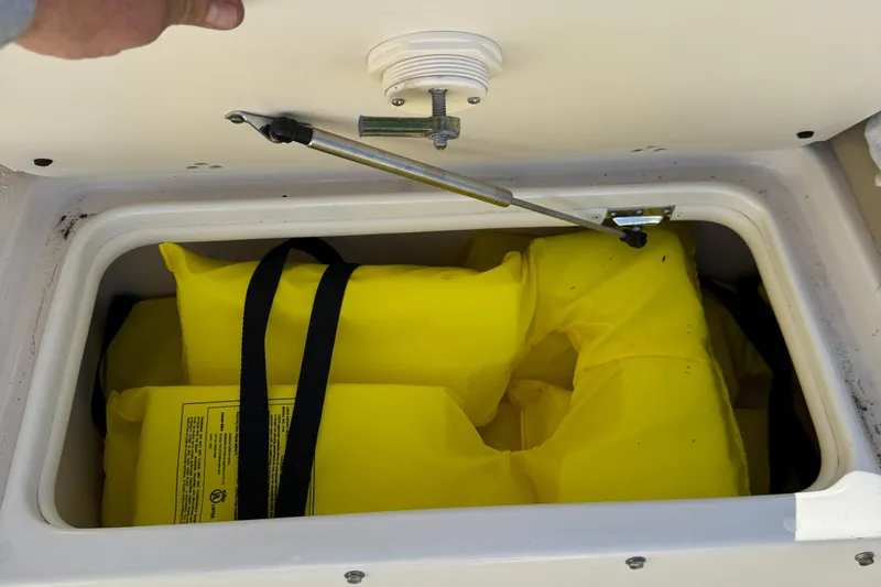 Slide: The Image of Storage compartment with yellow life jackets on a 2021 Carolina Skiff 23 Ultra Elite boat. - 18