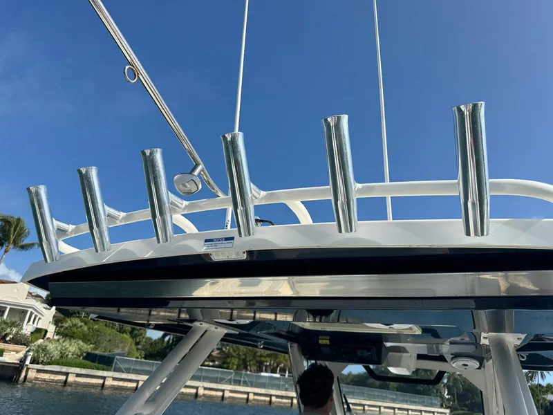 Slide: The Image of 2022 Pursuit S 328 Sport boat with rod holders and canopy, under clear blue sky. - 11