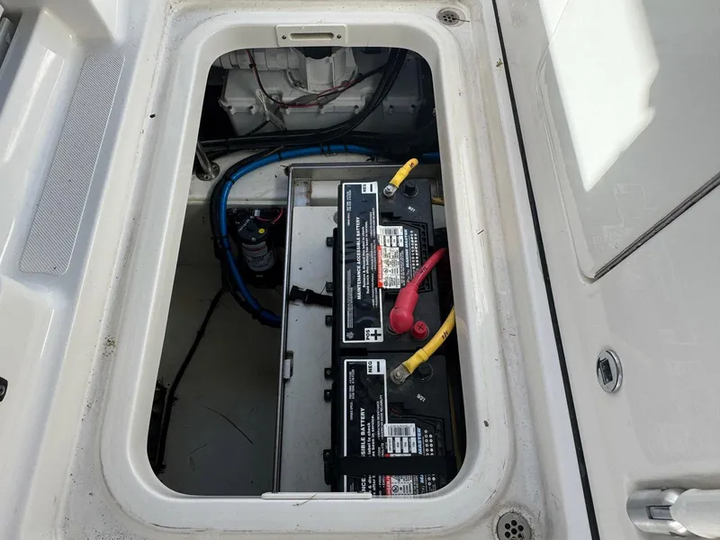 Slide: The Image of 2022 Pursuit S 328 Sport boat battery compartment with visible wiring and connections. - 14