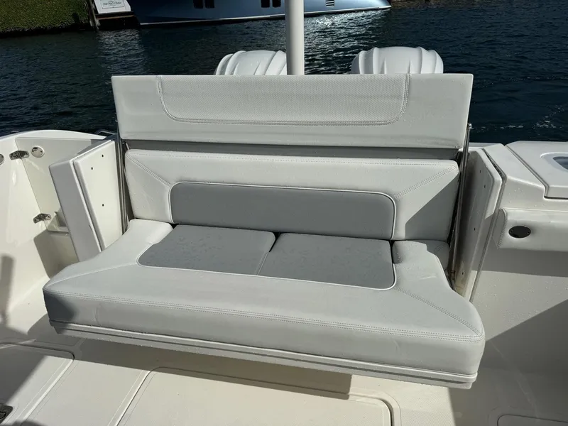 Slide: The Image of 2022 Pursuit S 328 Sport boat with cushioned seating by the water. - 15