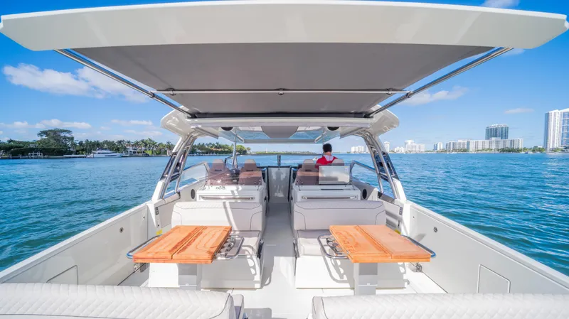 Slide: The Image of 2025 YOT 36 boat with open deck, wooden tables, and scenic waterfront view. - 22