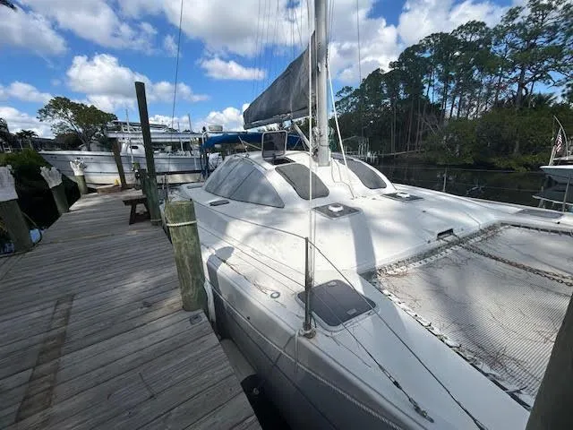 The Image of 1995 Lagoon TPI 37 catamaran docked, featuring sleek design and spacious deck under a blue sky. - 0