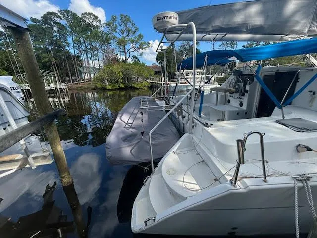 Slide: The Image of 1995 Lagoon TPI 37 catamaran docked in a serene marina setting. - 6