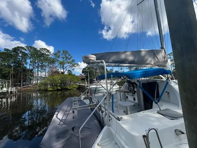 Slide: The Image of 1995 Lagoon TPI 37 sailboat docked on a serene waterway under a clear blue sky. - 7