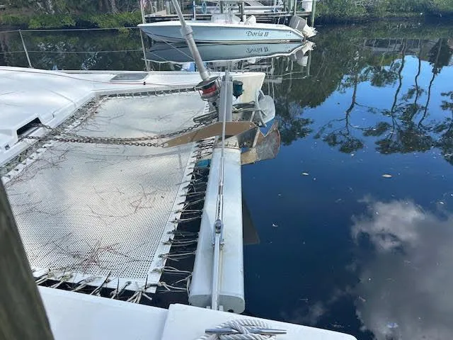 Slide: The Image of 1995 Lagoon TPI 37 catamaran docked on calm water with reflections of trees. - 8