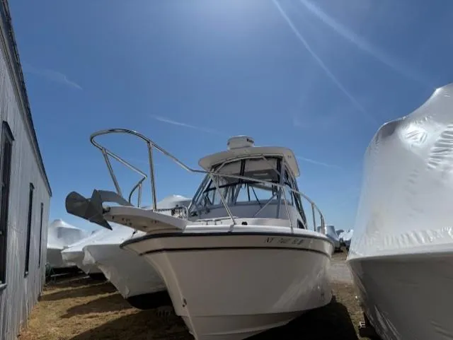 The Image of 2003 Grady-White Sailfish 282 boat under clear blue sky, docked beside covered vessels. - 0