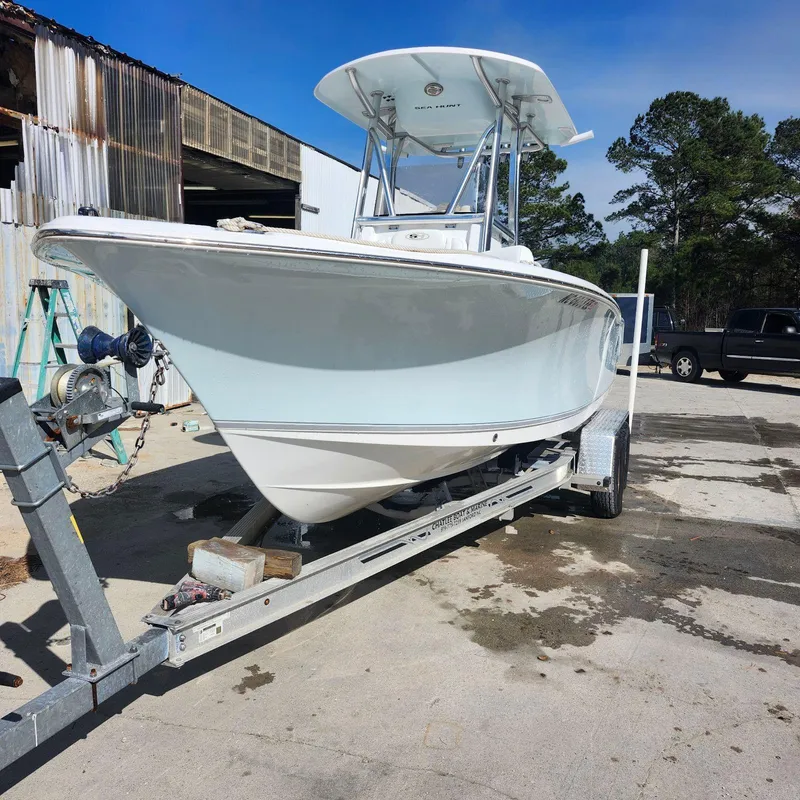 Slide: The Image of 2016 Sea Hunt Ultra 225 boat on trailer, parked outdoors near industrial buildings. - 0