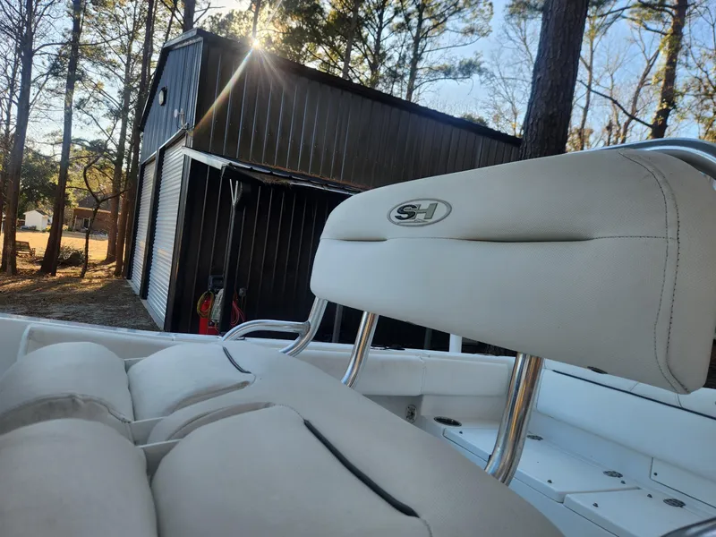 Slide: The Image of 2016 Sea Hunt Ultra 225 boat seat with sunlit backdrop and storage shed. - 10