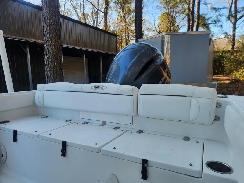 Slide: The Image of 2016 Sea Hunt Ultra 225 boat with white seating and outboard motor in wooded area. - 11