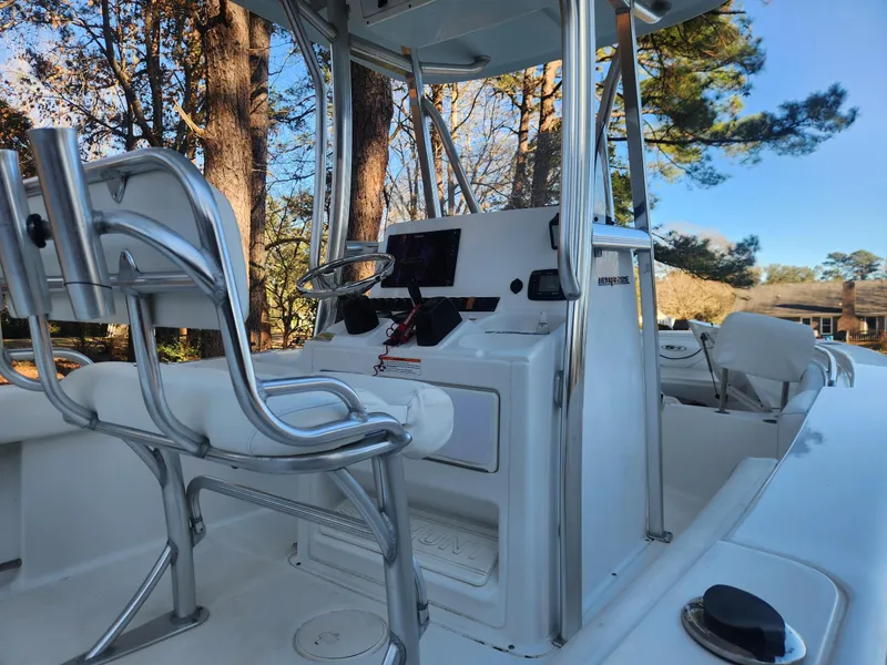 Slide: The Image of 2016 Sea Hunt Ultra 225 boat interior with steering console and seating, surrounded by trees. - 12
