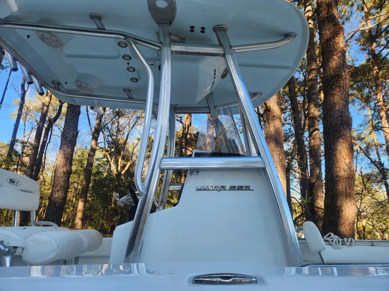 Slide: The Image of 2016 Sea Hunt Ultra 225 boat with T-top, surrounded by trees. - 14