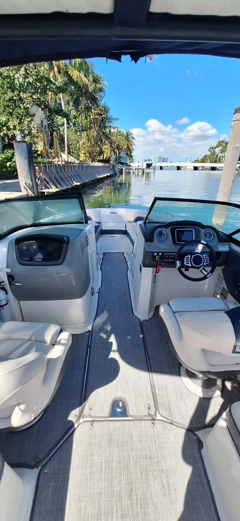 Slide: The Image of 2018 Chaparral Vortex 243 VRX boat interior with steering wheel, docked by palm trees. - 14