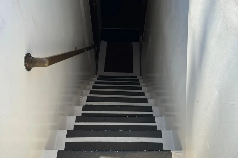 Slide: The Image of Narrow staircase with black and white steps, metal handrail on the left. - 43