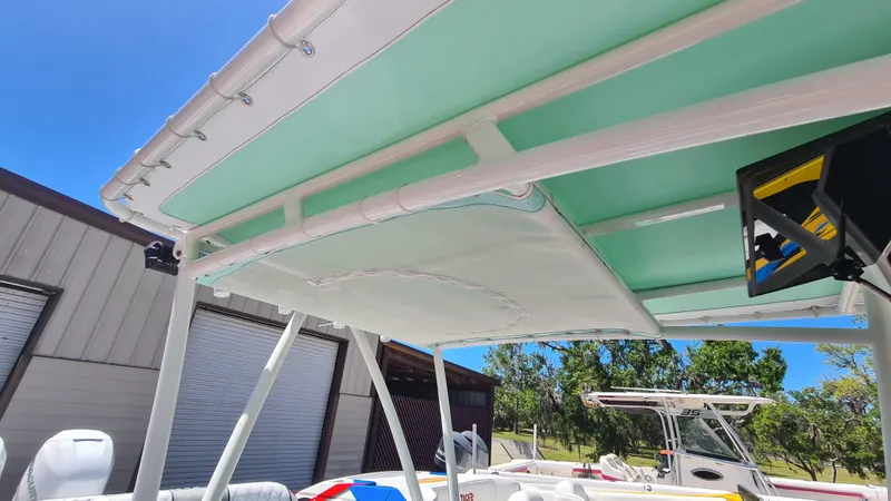 Slide: The Image of 2025 Custom Core 38 Center Console boat with a green canopy, docked near a building. - 12